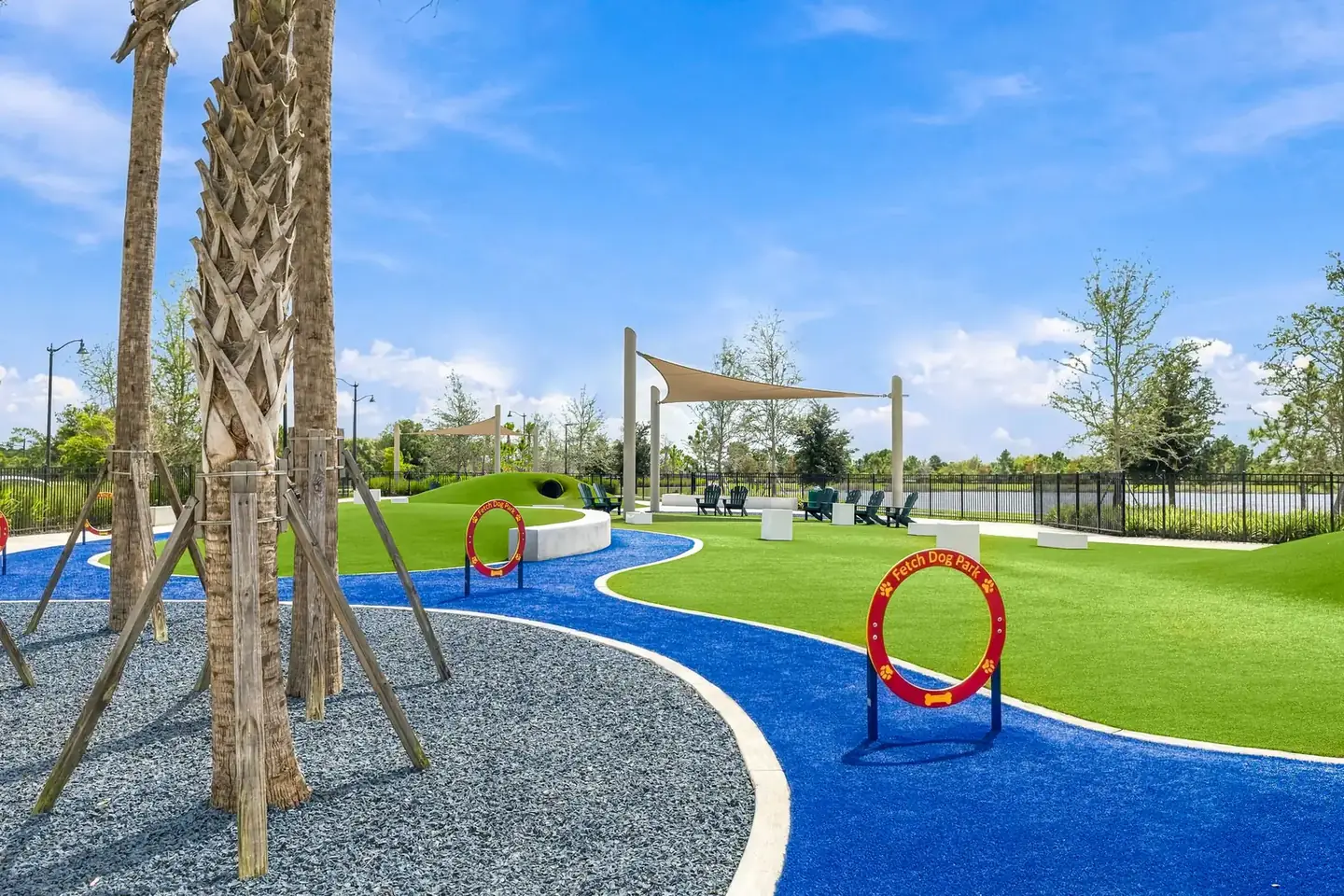 Agility hoop on turf beside a curving blue path at a Wellen Park dog park
